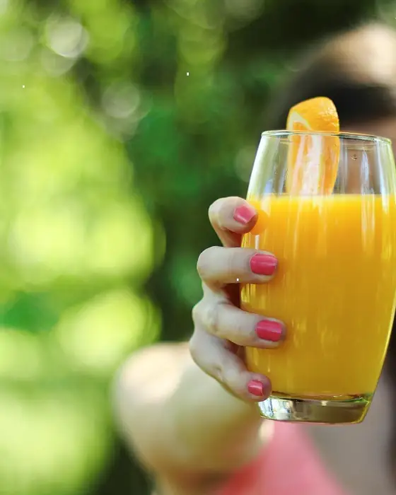 Hand met een glas vers sinaasappelsap